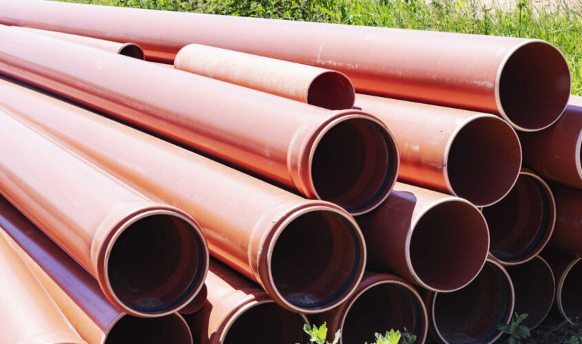 Orange sewer pipes at the construction site. Preparation for the installation of an underground sewer system. Wastewater disposal.