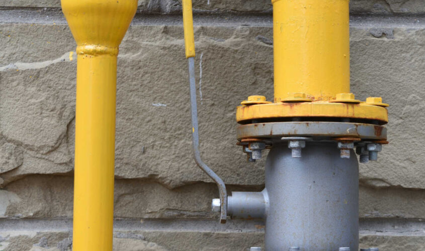 Gas pipe with a valve on the background of the stone wall of the house