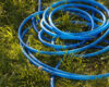 Watering hose lies on the grass, ground. Blue rubber tube in the